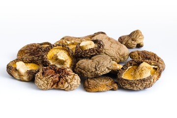 Dried shiitake mushrooms on a white backdrop reveal their detailed, rugged texture and deep organic hues.