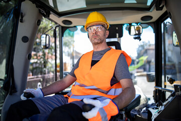 Construction worker operating machinery at a job site during daylight hours wearing safety gear and focused on the task