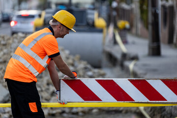 Construction worker manages safety barrier in urban setting during daylight hours