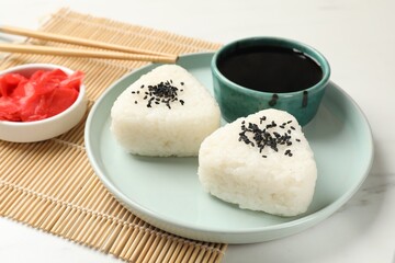 Rice balls (onigiri) served on light table, closeup. Traditional Japanese dish