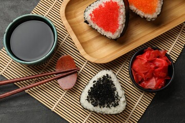 Tasty tobiko onigiri (Japanese rice balls) served on black table, flat lay