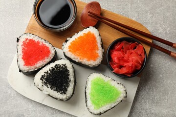 Tasty tobiko onigiri (Japanese rice balls) served on light grey table, top view