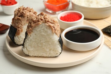 Tasty onigiri (Japanese rice balls) with tuna served on white marble table, closeup