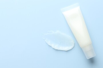 Moisturizing lip balm and tube on light blue background, top view. Space for text
