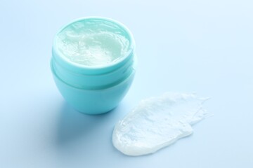 Moisturizing lip balm and jar on light blue background