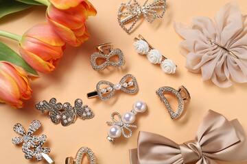Beautiful hair clips, bow and tulips on beige background, flat lay