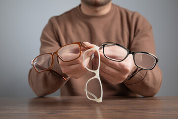 Caucasian technician holding different eyeglasses.
