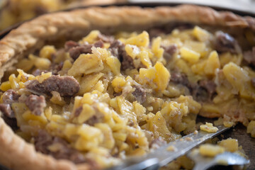 Capturing the essence of comfort food, a close up reveals a golden brown meat pie filled with savory potatoes, baked to perfection