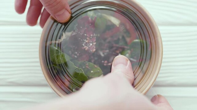 Closeup of man paking up a fresh healthy salad to a zero waste container to go. Food delivery, healthy food concept.