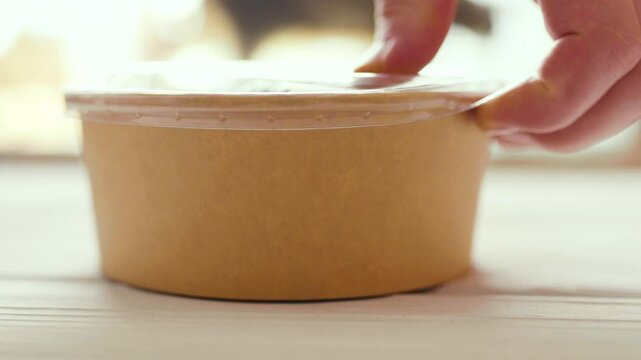 Closeup of man eating a fresh healthy salad from a zero waste container to go. Food delivery, healthy food concept.