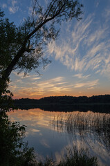 Summer landscape at twilight of West Three Lakes with reflections in calm water,  Michigan, USA