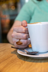 Female hands with a ring holding a coffee cup