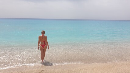 A Woman in a Red Bikini Walking into the Turquoise Waters of the Ocean