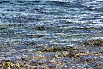 Transparent sea water above pebbles in the shallow water