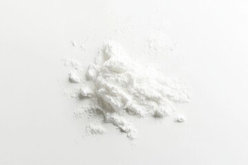 A pile of white powder, possibly flour or cornstarch, is scattered on a white background.