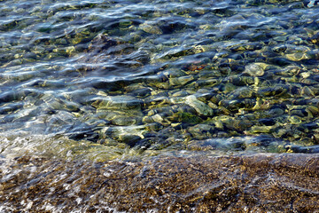 Transparent and smooth sea water above round pebbles