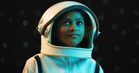 Girl, thinking and astronaut with space helmet at night for galaxy adventure, journey or universe. Female person, face or thoughtful teenager with dream, ambition or spacesuit in wonder or curiosity © peopleimages.com