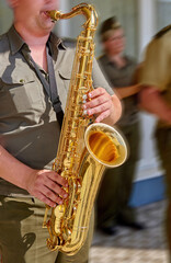 Obraz premium A musician skillfully plays a golden saxophone during an outdoor gathering on a sunny day in the heart of a vibrant city