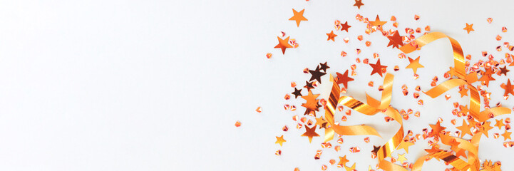 Banner with golden ribbons, stars and crystals confetti on a blue background.