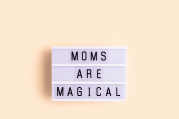 Moms are magical. White lightbox with letters on a beige background.