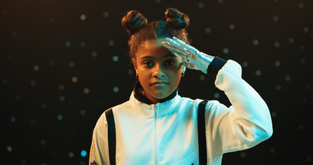 Girl, portrait and astronaut with salute in spacesuit at night for galaxy adventure, journey or travel. Female person, young teenager or child with recognition for respect on a dark studio background