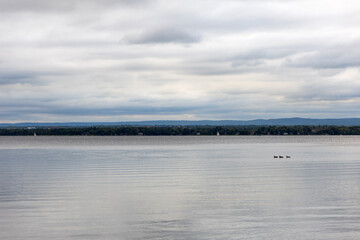 Cloudy sky and river on an overcast day. Riverside in summer.
