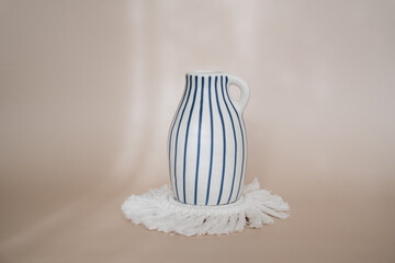 modern striped blue and white vase standing on a white coaster. Minimal boho styled interior design, living room or bedroom decor.	