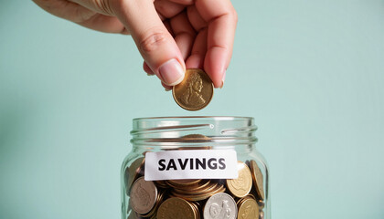 Hand depositing coin into savings jar, commitment to financial goals