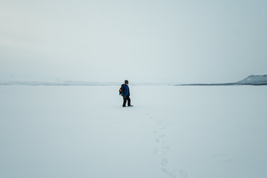 Man stood on frozen snowy lake in the arctic, Kilpisjarvi, Finnish Lapland.