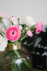 Bouquet of pink and white ranunculus flowers in a glass vase	