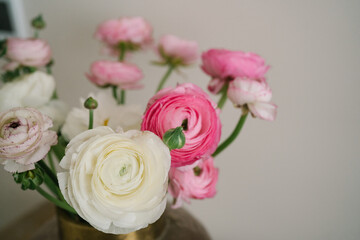 Bouquet of pink and white ranunculus flowers in a glass vase	