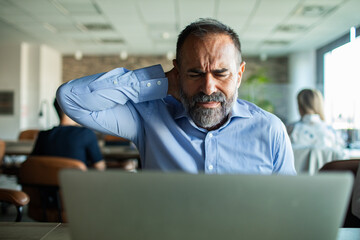 Stressed businessman working on laptop in office