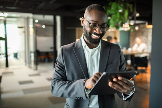 Smiling black businessman using tablet in modern office