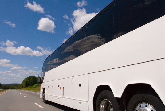 tour bus on highway with blue sky and white clouds