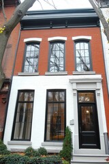 Obraz premium Renovated red brick house showcasing classic architecture in an urban neighborhood with large windows and modern design elements during a crisp autumn day