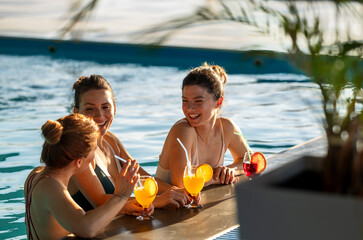 Female friends enjoy refreshing drinks by the poolside on a sunny day