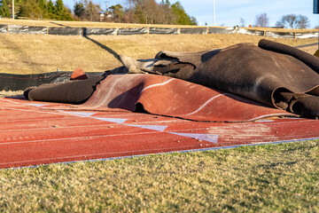 Photo showing a running track reconstruction with the existing track surface being removed.