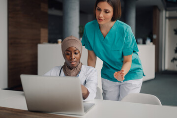 Medical professionals collaborating on laptop in hospital setting