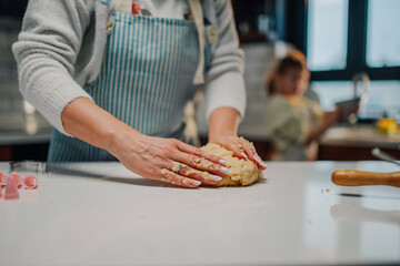 Woman kneading dough on kitchen counter with child in background