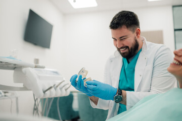 Dentist showing teeth model to patient in modern clinic