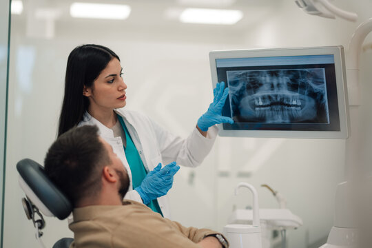 Dentist showing teeth x ray to patient in modern clinic
