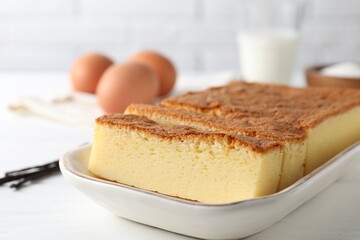 Tasty Japanese Castella sponge cake and ingredients on white table, closeup