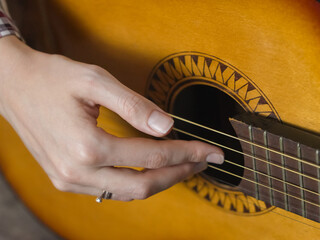Close-up view of a musician's hands expertly positioning fingers on the strings of an acoustic...