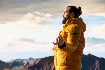 Pleased content hiker doing a meditation session for stress relief in nature, relaxing for wellness and balance on top of the mountain. Young hiker traveler meditating for mindfulness.