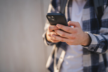 young man student stand in front white wall and use mobile phone