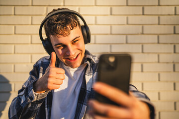 man student stand in front white wall have video call on mobile phone
