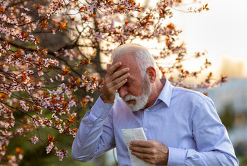 Old man having headache because of pollen allergy in spring