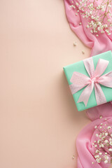 Vertical gift box in mint green with pink ribbon, styled with pink fabric and flowers for a festive mood