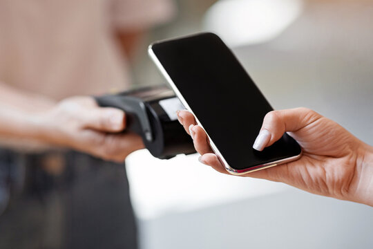 Wireless Payment. Close up of female hand using smartphone, paying contactless for bill at cafe