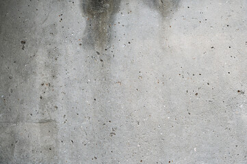 A textured concrete wall with cracks, stains, and weathered discoloration, creating an abstract and grunge aesthetic with a raw, urban feel.